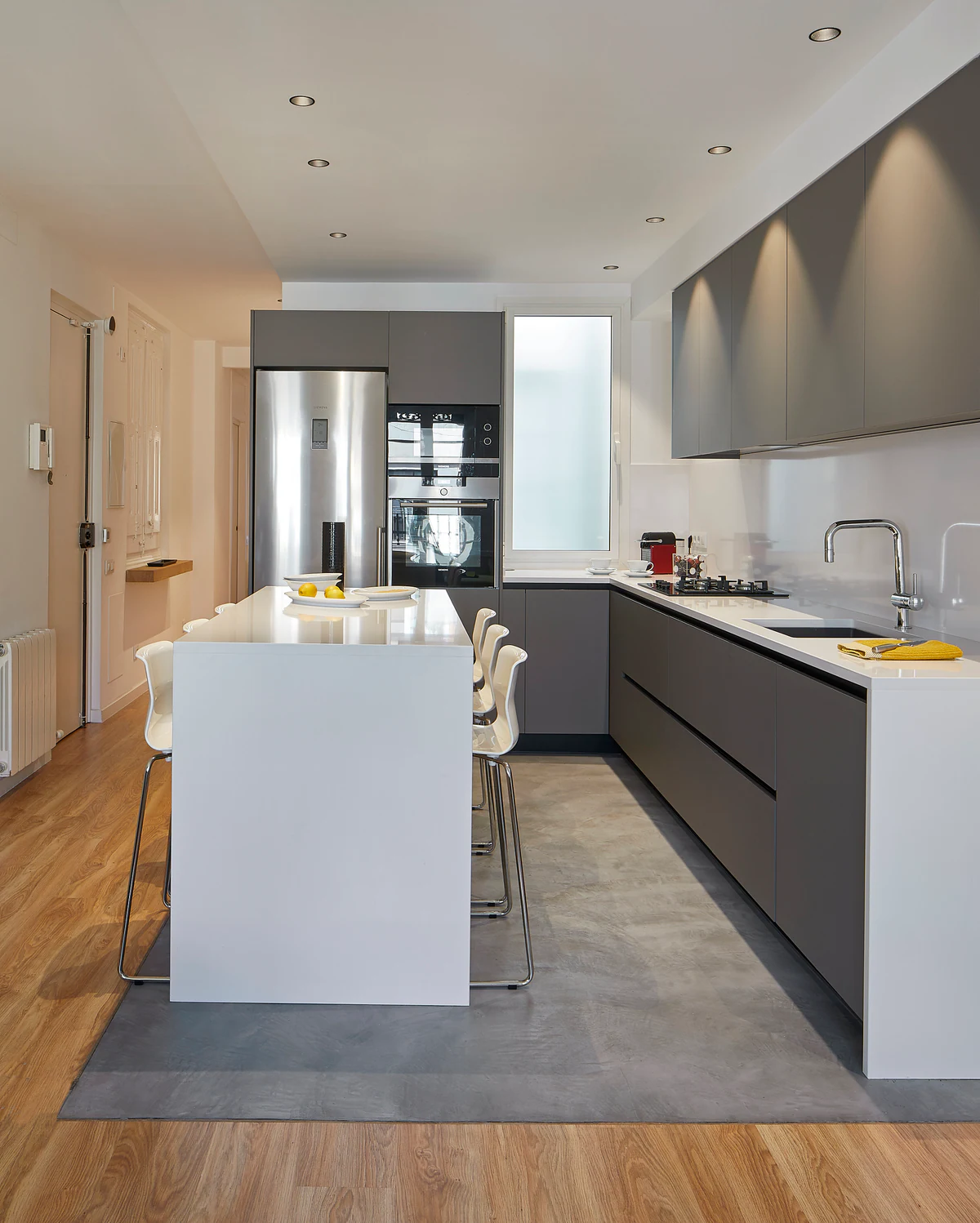 Long kitchen with an island and spotlights aimed at the cabinetry