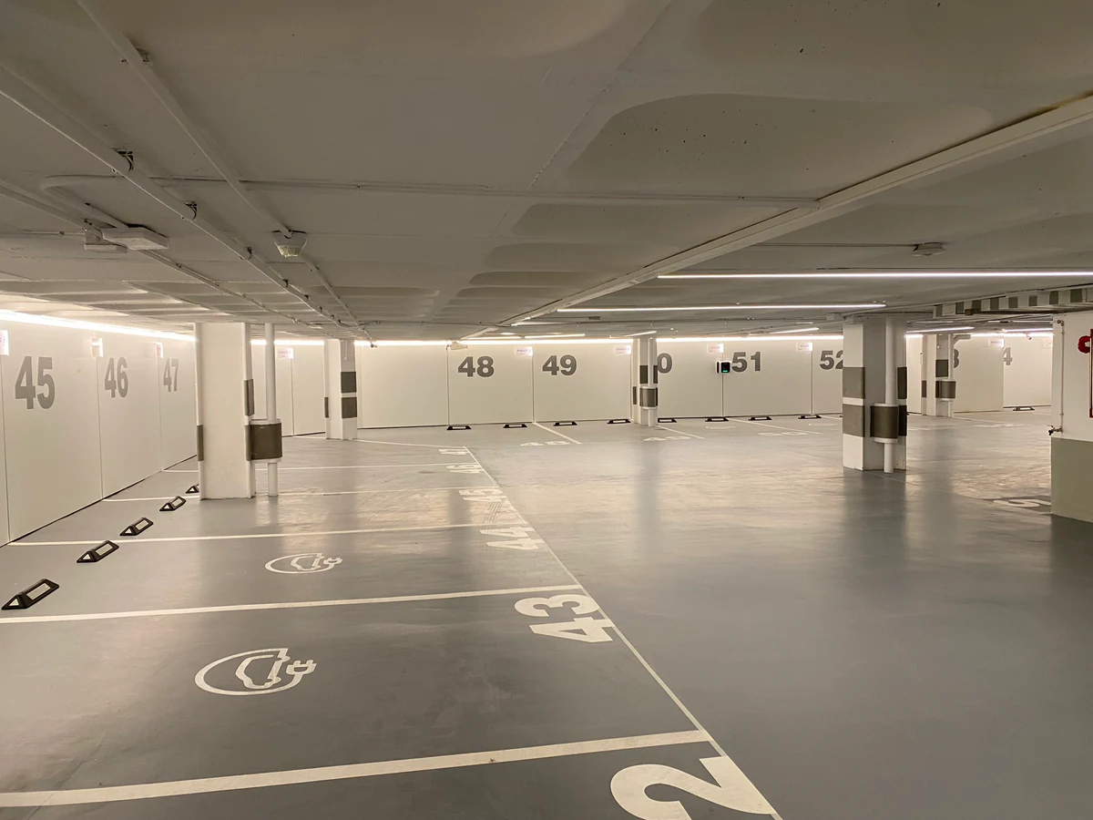 Aparcamiento con iluminación lineal en el techo y plazas numeradas