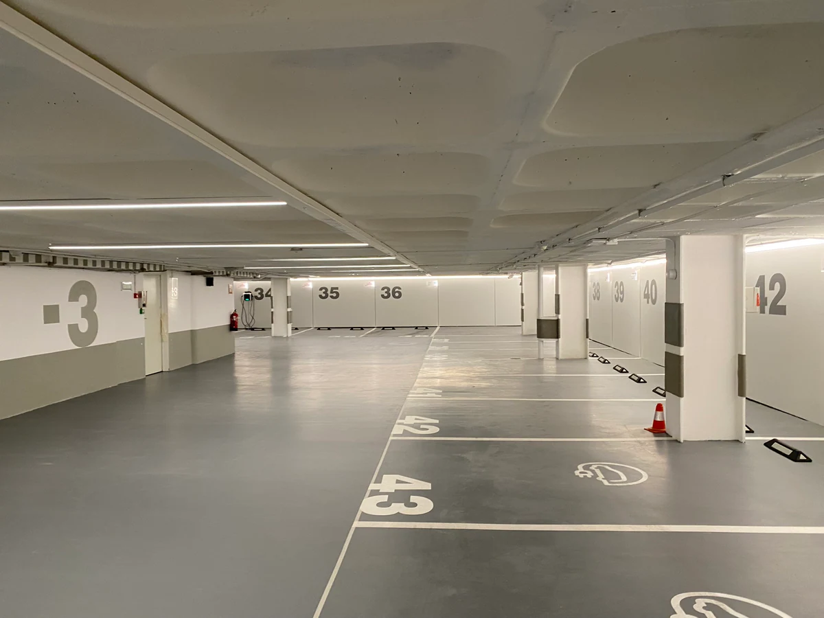 Car park with continuous lines of light suspended from the ceiling
