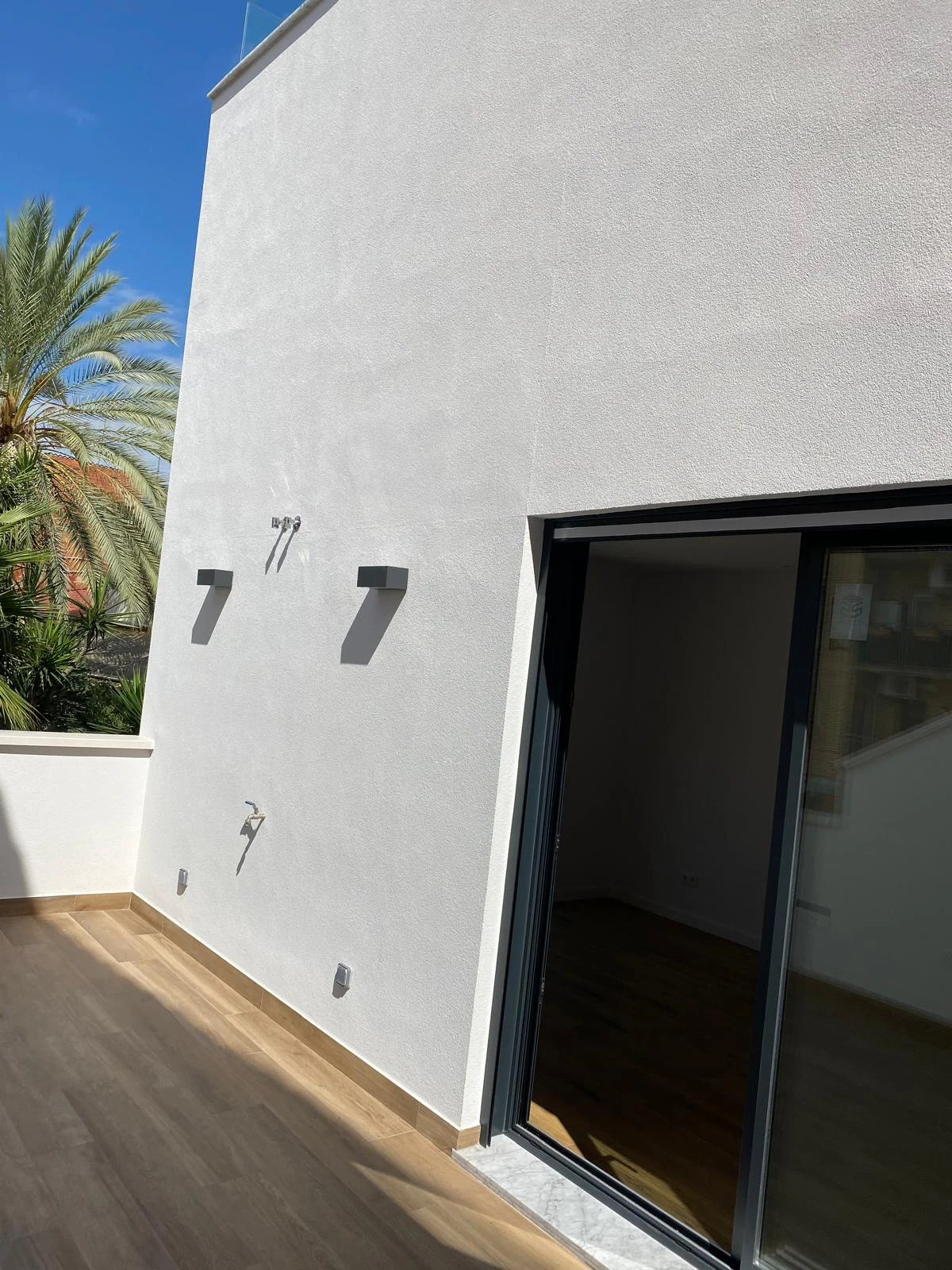 White terrace façade with wall lights beside a glass door