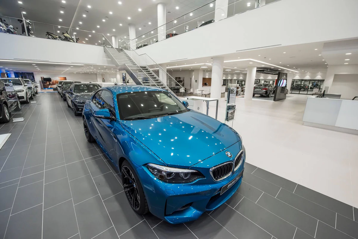 Vehicles on display under lines of light and ceiling spotlights