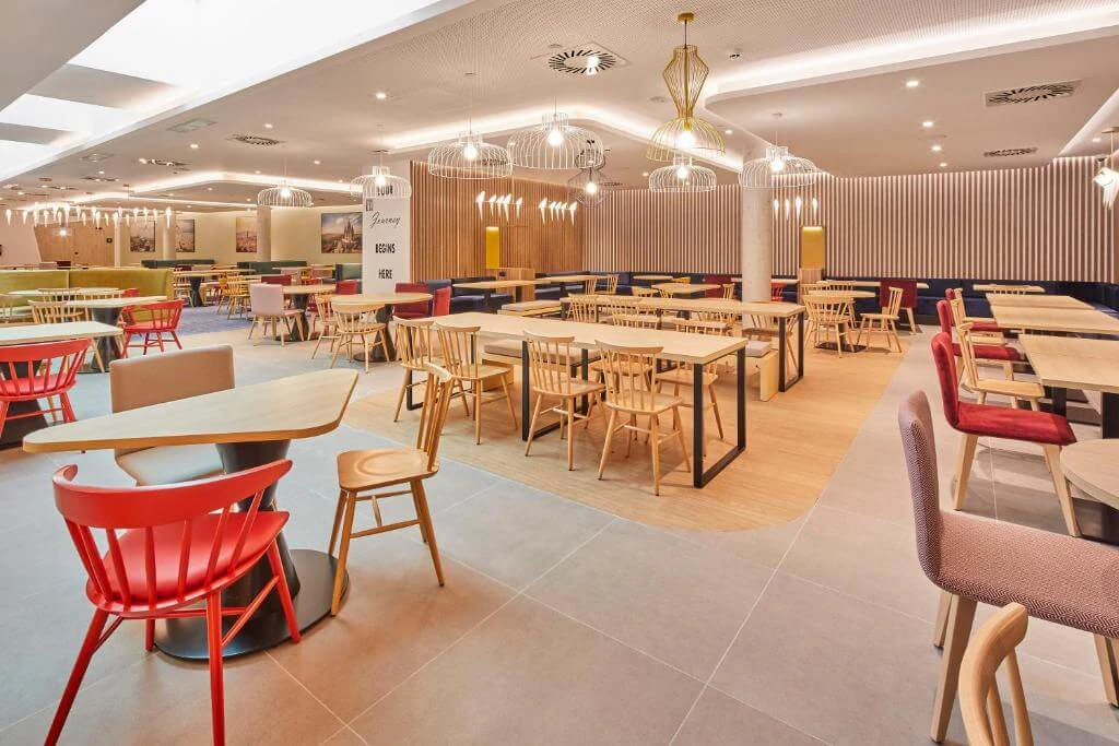 Dining room with tables, colourful chairs and suspended luminaires