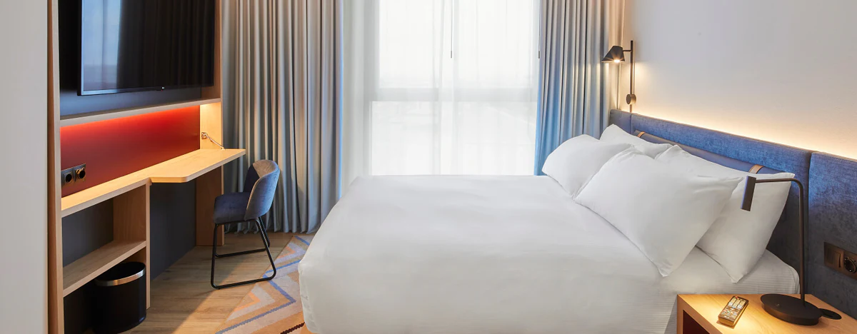 Bedroom with an illuminated headboard, desk and window