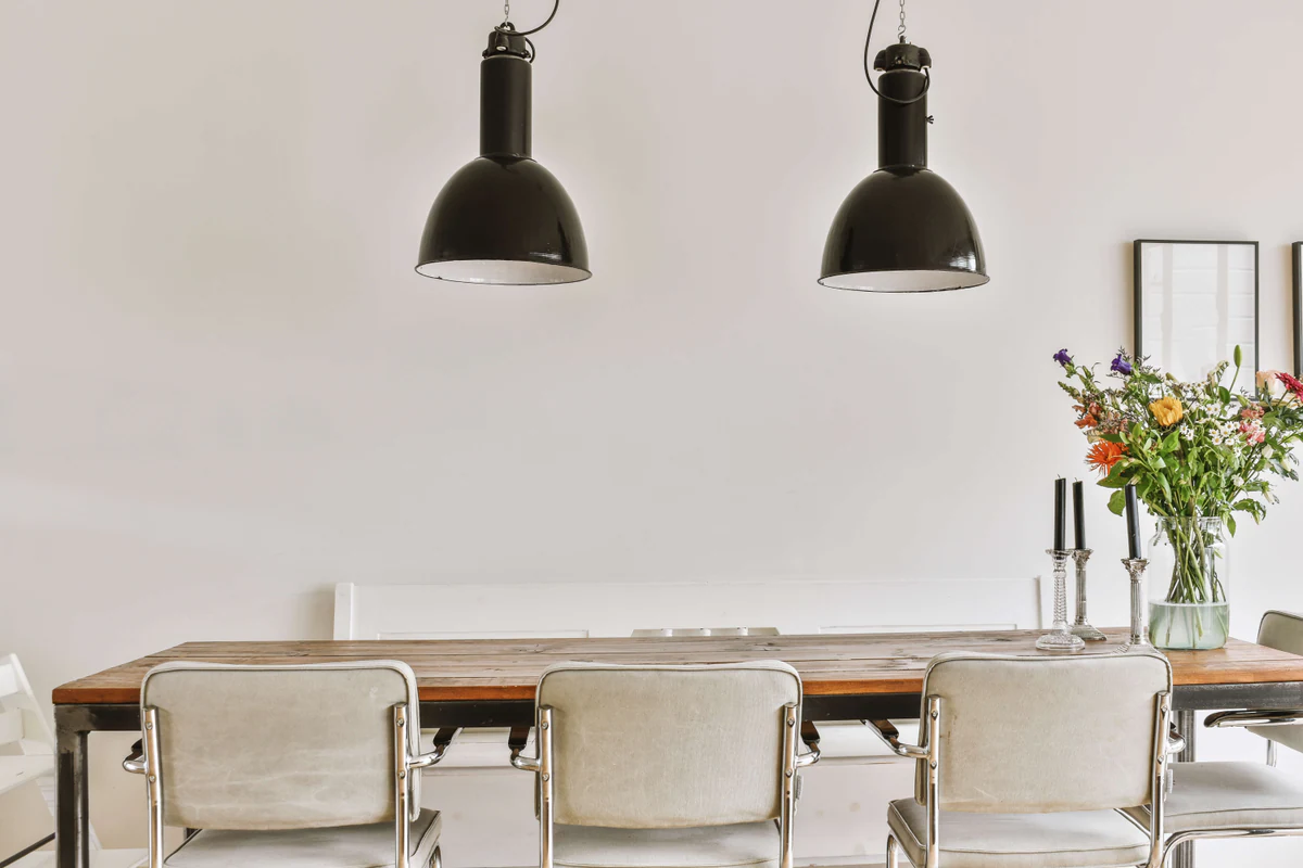 Dining room with two black lamps above a wooden table