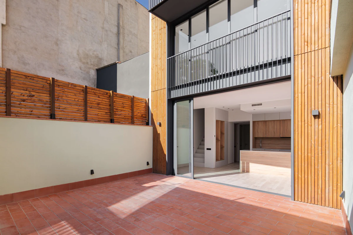 Courtyard between façades with timber cladding and outdoor wall lights
