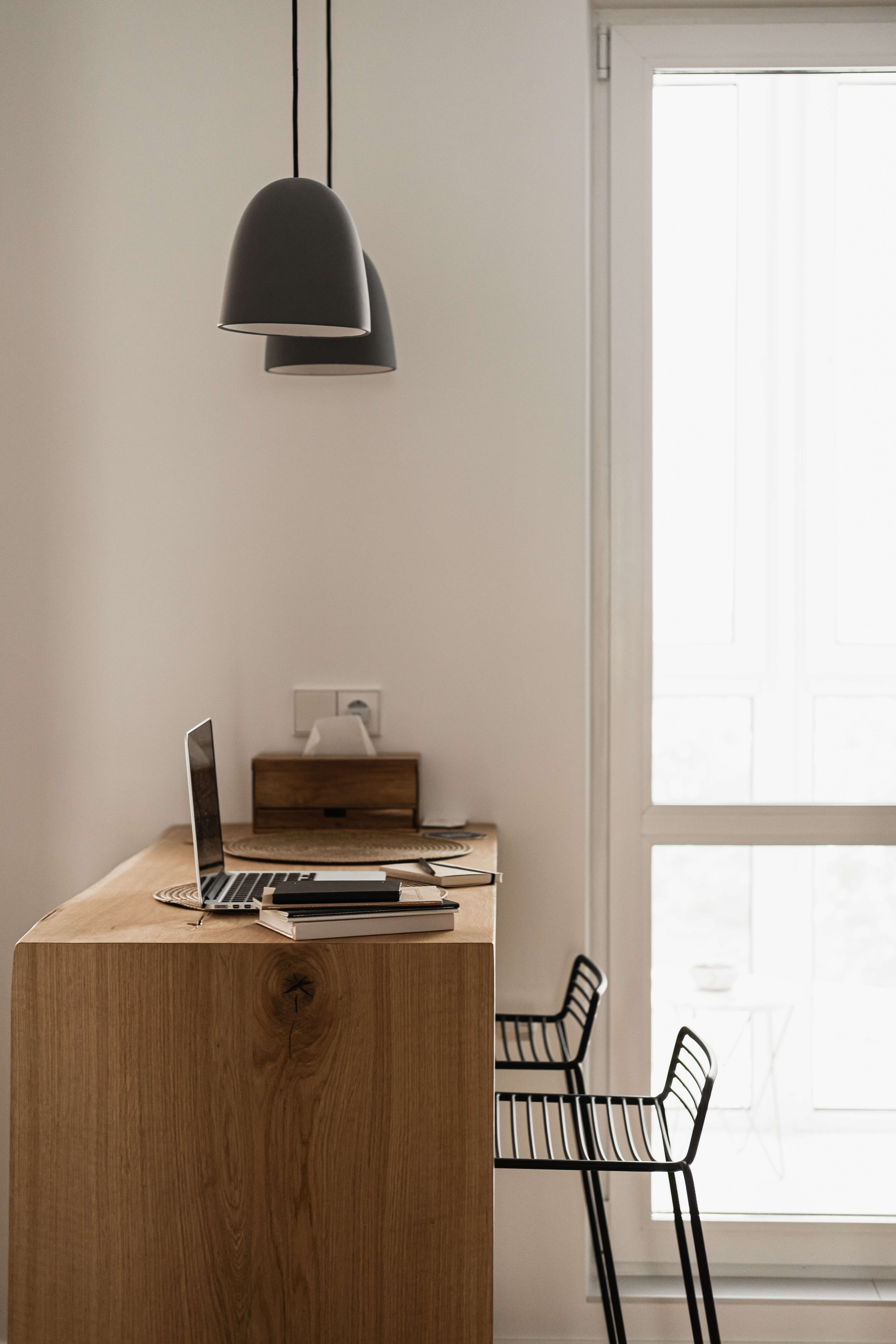 Luminaria suspendida sobre una mesa de madera junto a una ventana